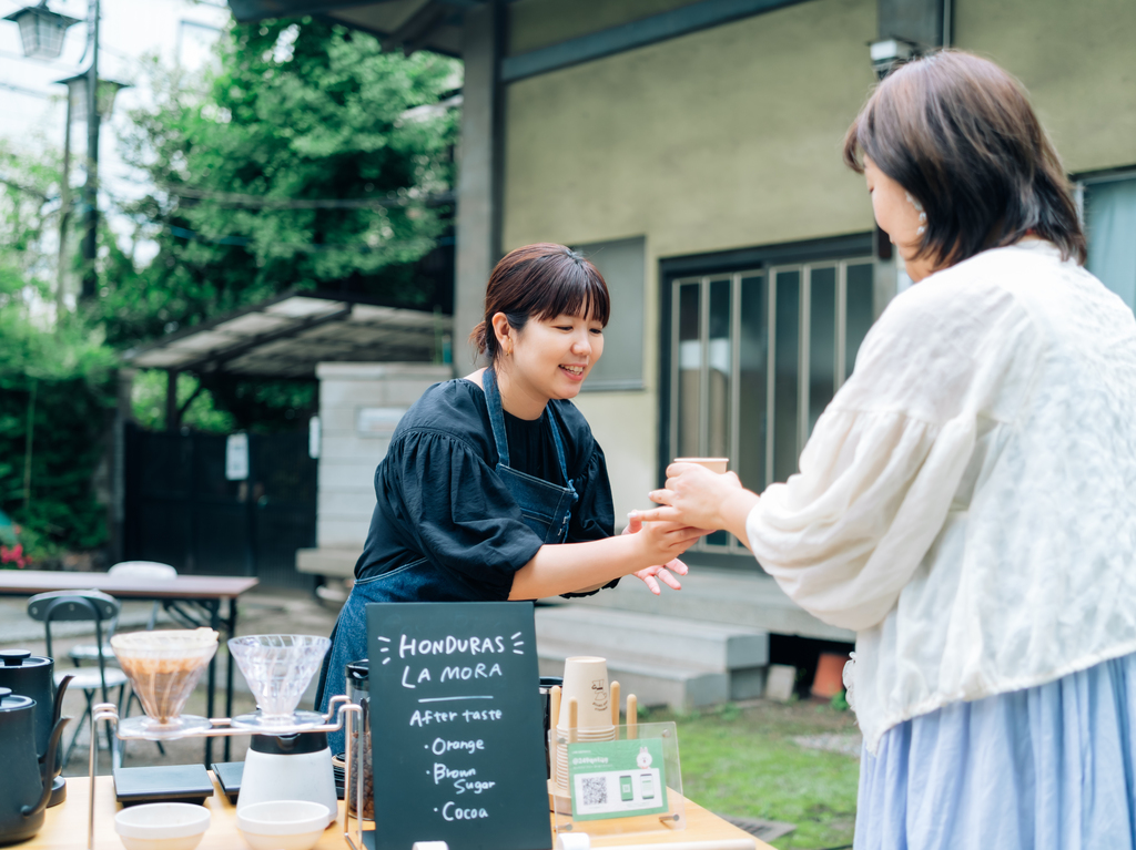 コーヒーを手渡すMutsumi