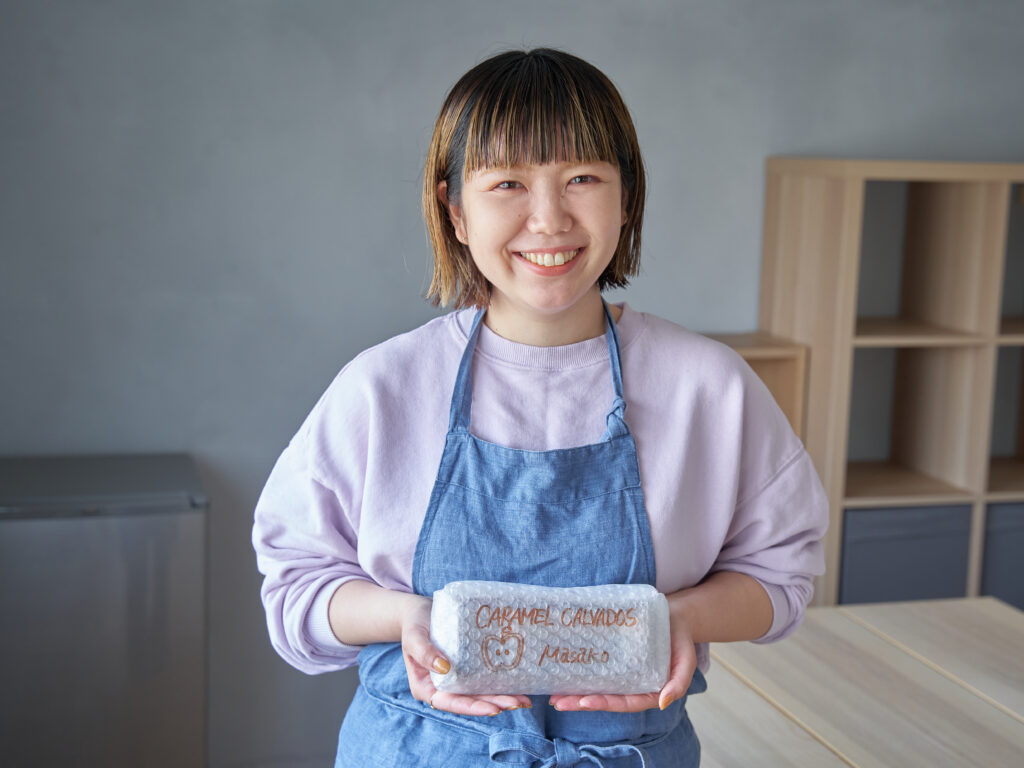 「Masako Mutsumi by Zengakuji free coffe」コンセプターのMutsumi。手にしているのは、スペシャルティチーズケーキで初となる限定フレーバー「キャラメル」