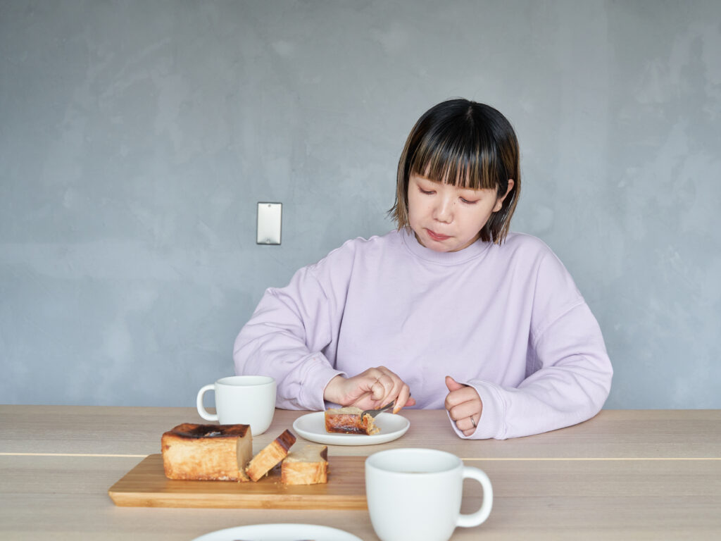 「Masako Mutsumi by Zengakuji free coffe」コンセプターのMutsumi。試食しているのは、スペシャルティチーズケーキで初となる限定フレーバー「キャラメル」